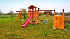 A wooden playground with a slide, swings, and climbing structures. - Terraced Houses in Sarbinowo Near Beach (Mielno)