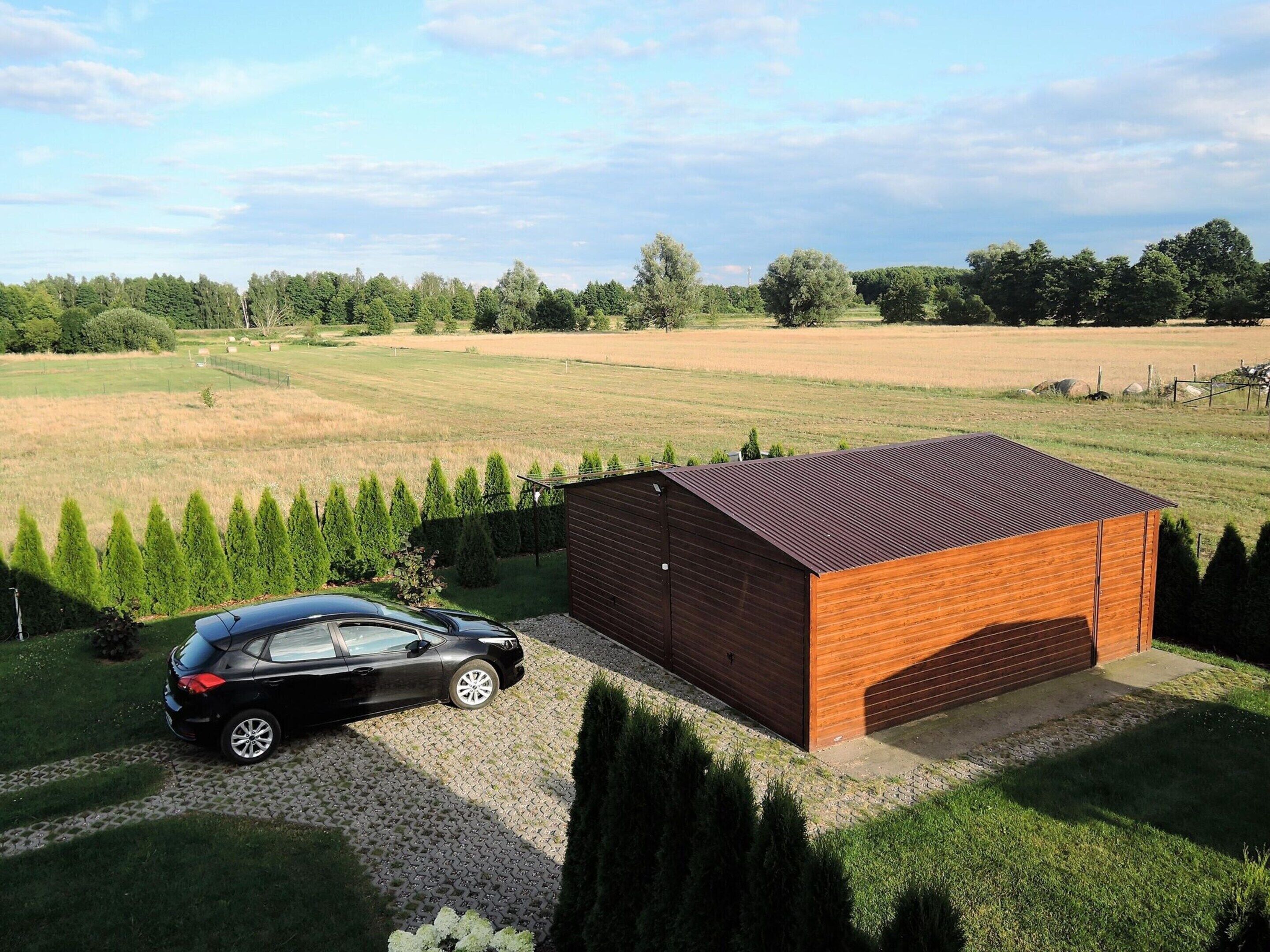 A modern building with a red roof, a paved driveway, and a car parked in front.