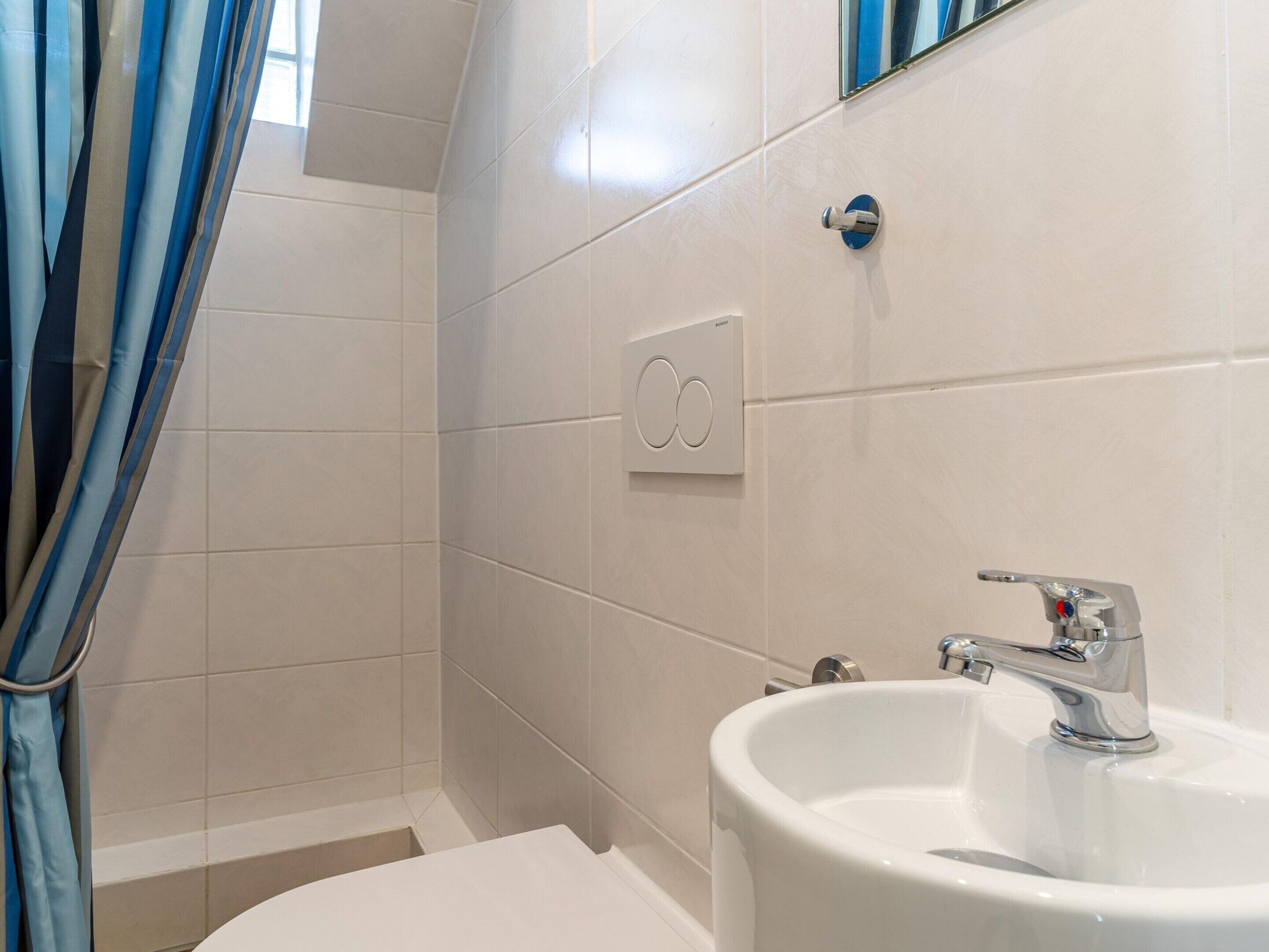 A bathroom with a white sink, a mirror, and a shower area.