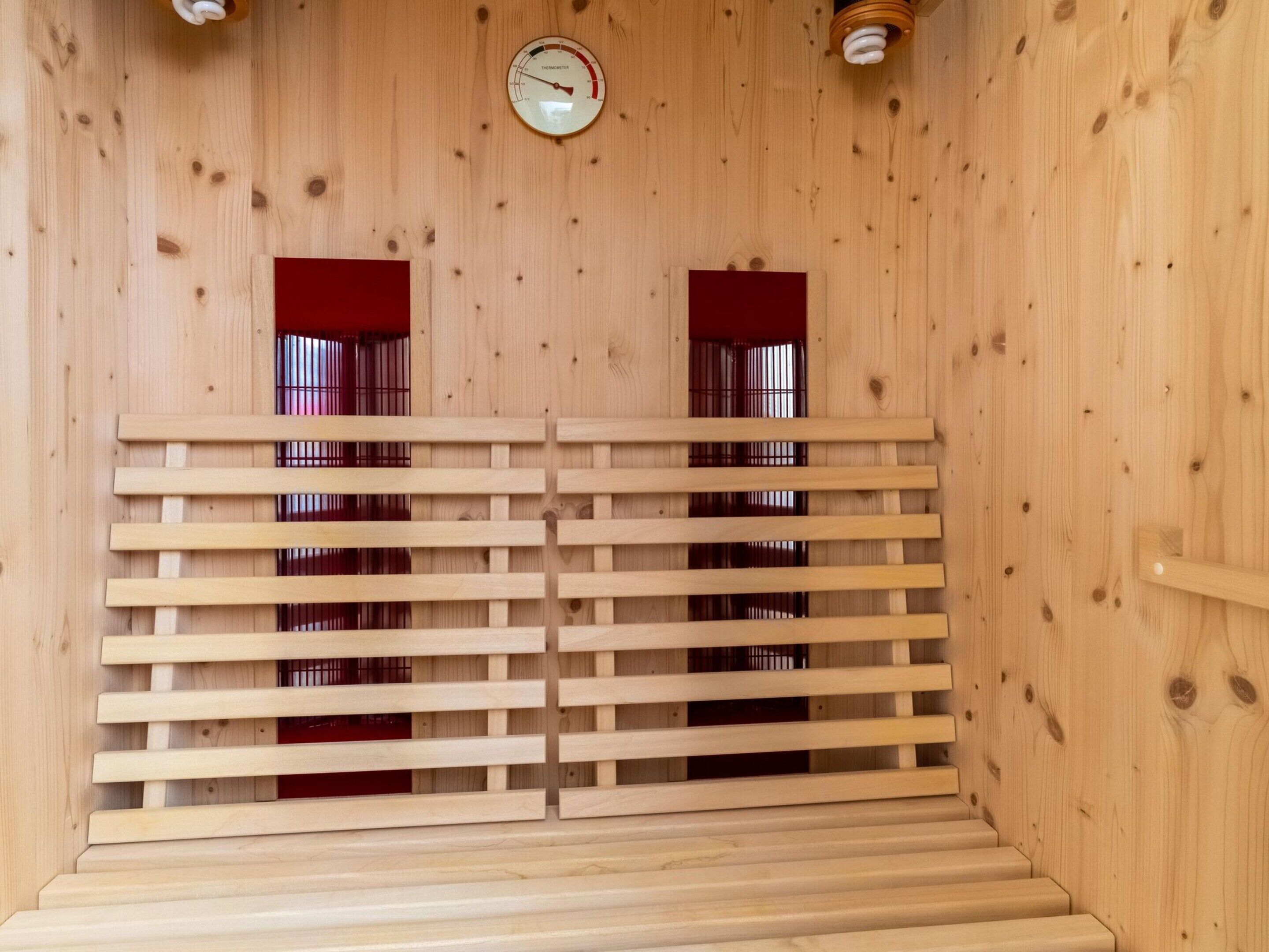 A sauna with wooden walls, a slatted bench, and two small windows with red frames.