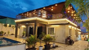 Une maison à deux étages avec un balcon, une piscine et des plantes en pot.