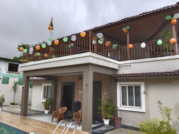 A two-story house with a balcony decorated with balloons and a flag. - Raj Heritage Ghorle By GRB (Murbad)