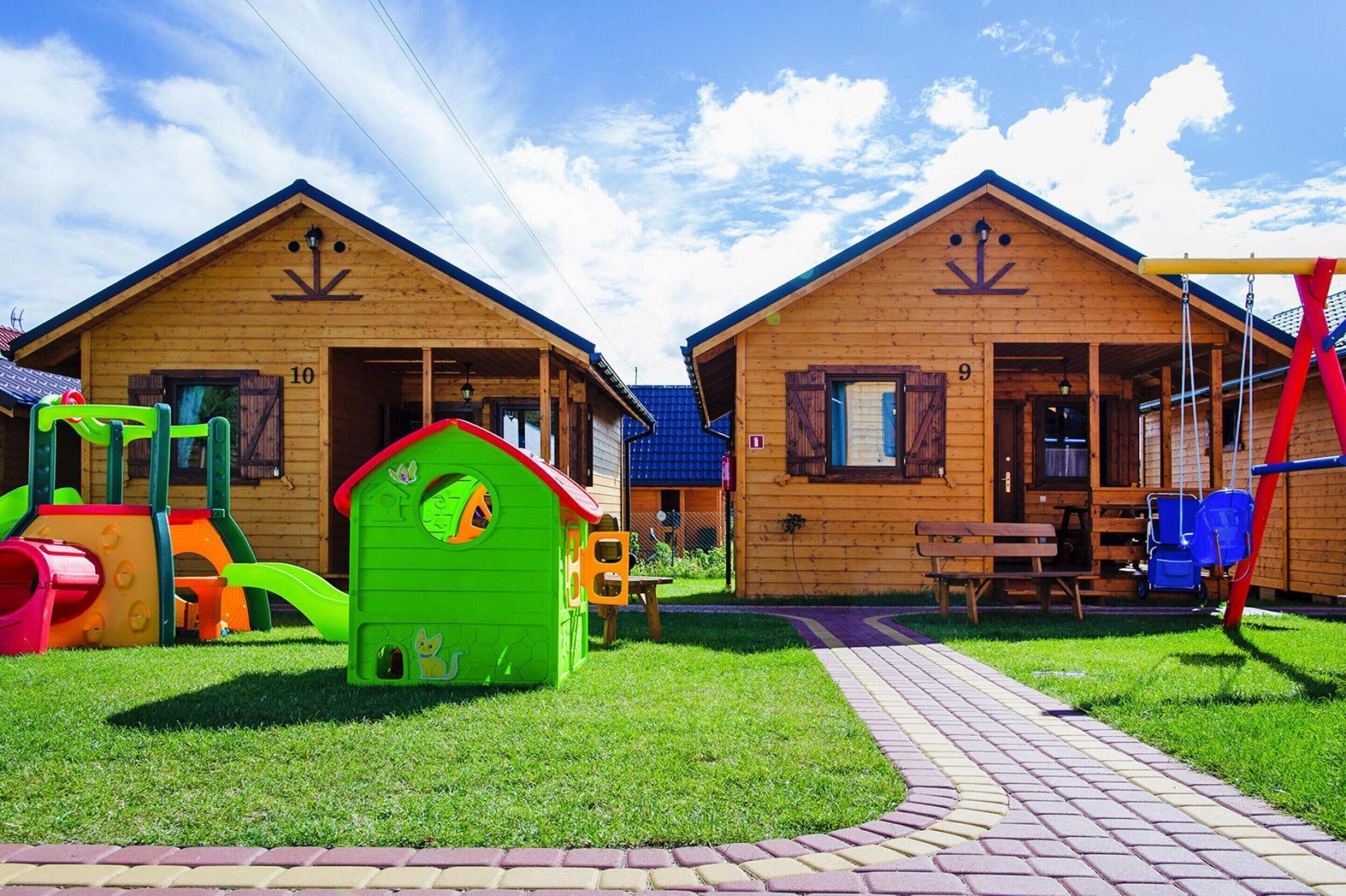 Two wooden cabins with a playground in front.