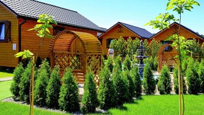 Une rangée de cabanes en bois, avec un jardin bien entretenu et une structure centrale également en bois.