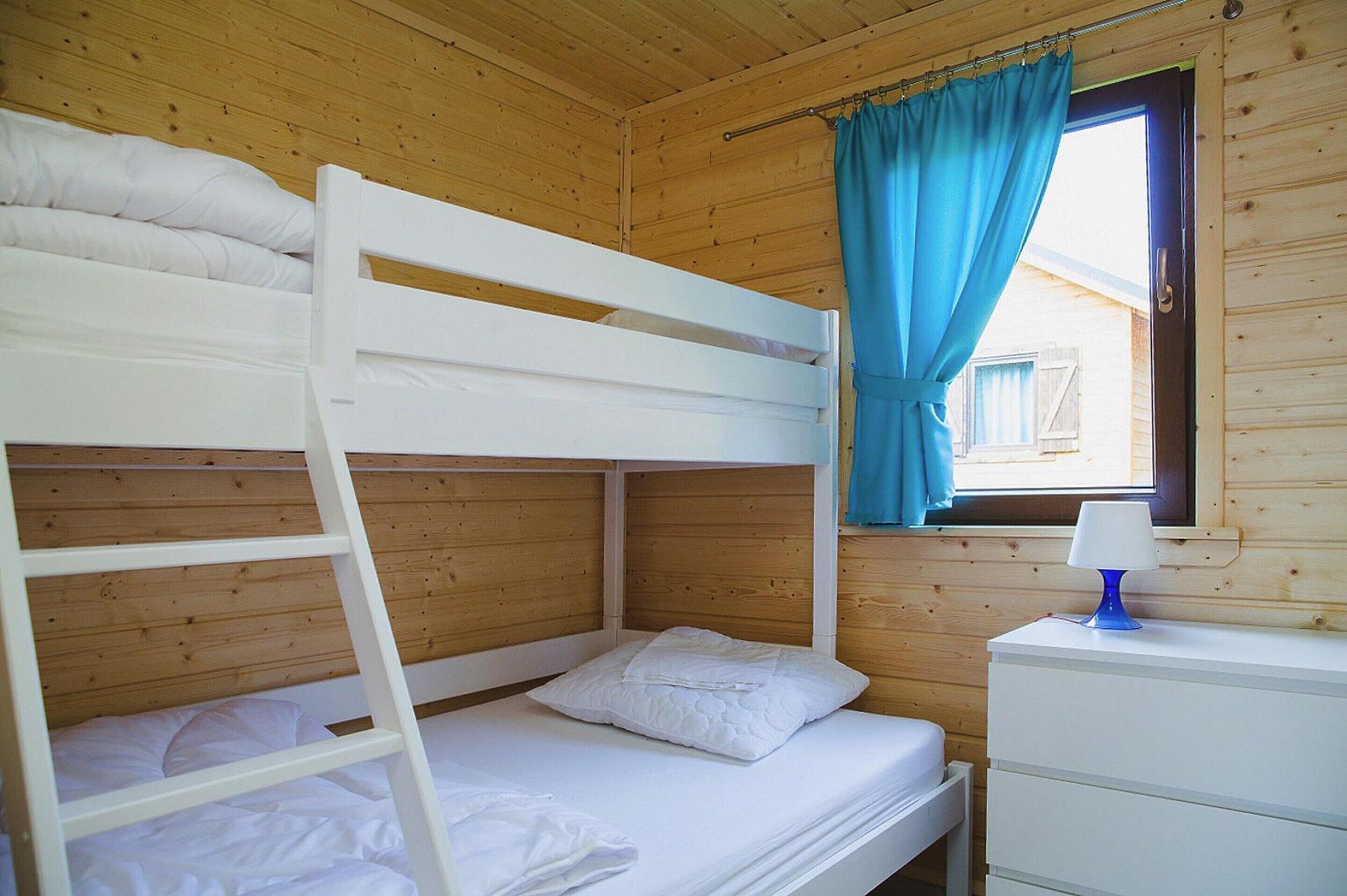 Une chambre avec un lit superposé, une fenêtre et une commode.