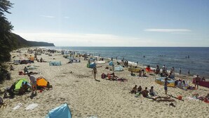 Une plage bondée, avec des tentes, des parasols et des gens qui se détendent.