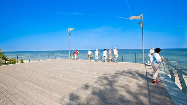 A wooden boardwalk with people walking along it, overlooking a body of water. - Holiday Home in Rewal Near Baltic Beach (Rewal)