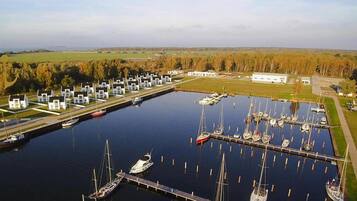 A marina with multiple docks and boats, surrounded by a residential area with white houses and a large building.