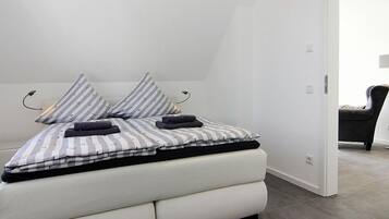 A modern bedroom with a bed, pillows, and a chair.