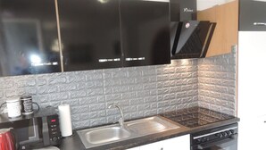 A kitchen with black cabinets, a granite countertop, a stainless steel sink, a microwave, a red kettle, and a stove. - Apartment in Misdroy Near Baltic Beach (Międzyzdroje)