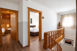 Habitación de hotel con piso de madera, cama, mesita de noche, lámpara y ventana con cortina.
