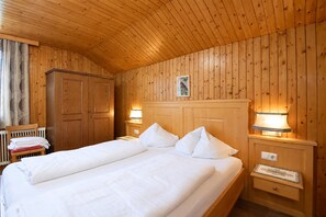 Una habitación con paneles de madera, una cama, dos lámparas de noche, una mesita de noche, un armario y un radiador.