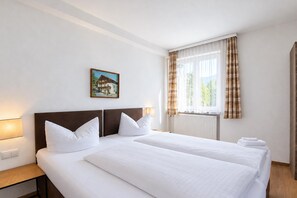 A hotel room with a large bed, two pillows, a nightstand, a lamp, a window with curtains, and a painting on the wall. - Chalet in Fugen Near Spieljochbahn (Fuegen)
