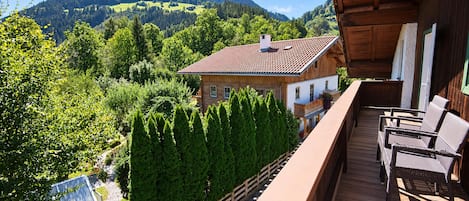 A wooden balcony with outdoor furniture overlooking a mountainous landscape.