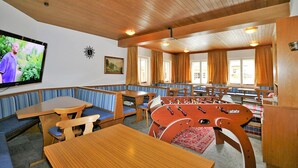 Ein gemütliches Zimmer mit Holzmöbeln, einem Tischfußballspiel und einem Fernseher an der Wand.