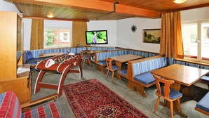 Ein gemütliches Zimmer mit Holtmöbeln, einem Kicker und einem Fernseher.