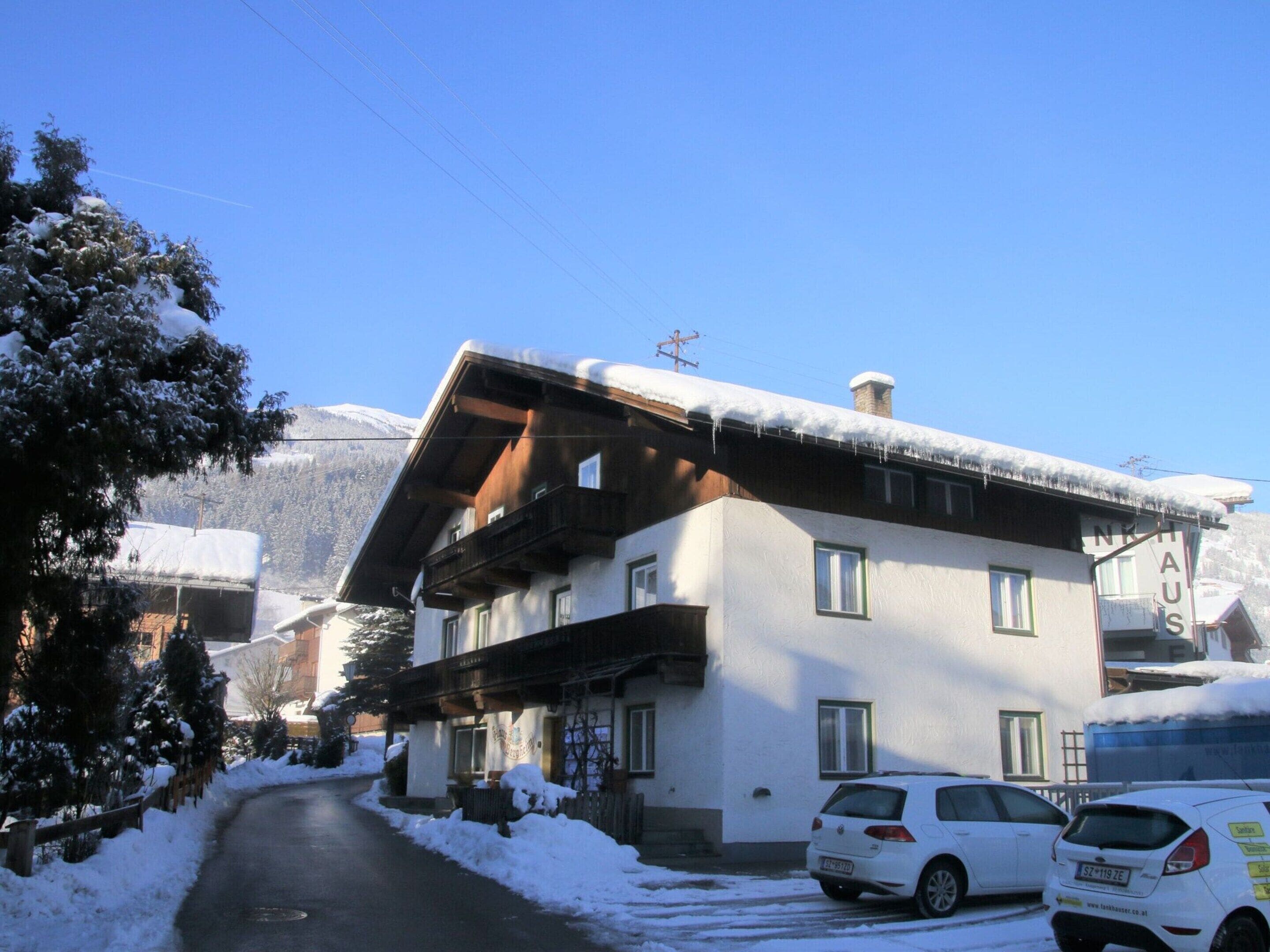 Un bâtiment à deux étages, doté d’un toit en pente, d’une cheminée bien visible et d’une enseigne indiquant qu’il s’agit d’une station de ski.