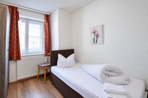 A bedroom with a bed, a chair, a radiator, and a window with curtains. - Chalet in Fugen Near Spieljochbahn (Fuegen)