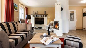 A living room with a sofa, a coffee table, a fireplace, a television, and a bookshelf. - Apartment in Veringendorf Near Swabian Alb (Veringenstadt)
