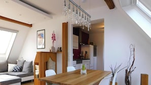 A dining area with a wooden table and white chairs, a kitchen in the background, and a skylight above. - Apartment in Veringendorf Near Swabian Alb (Veringenstadt)