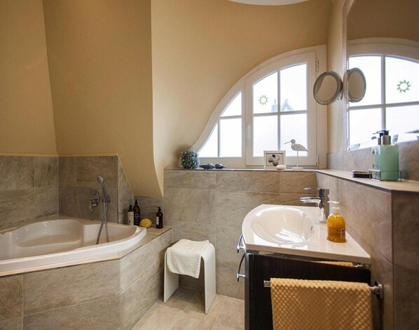 A modern bathroom with a freestanding bathtub, a vanity with a sink, and a large arched window. - Apartment in Veringendorf Near Swabian Alb (Veringenstadt)