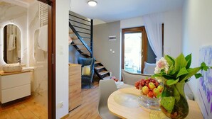 A modern living room with a staircase, a dining area with a vase of fruit and flowers, and a bathroom with a marble sink. - Holiday Homes in Mielenko (Mielno)