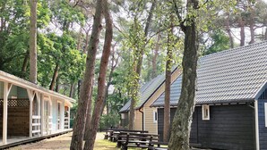 A rustic cabin with a wooden exterior, surrounded by tall trees and a covered porch. - Cottage Near the Sea, Pobierowo (Rewal)