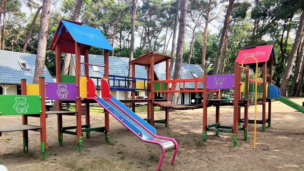 Ein Spielplatz mit verschiedenen Spielgeräten, darunter Rutschen und Kletterbereichen.