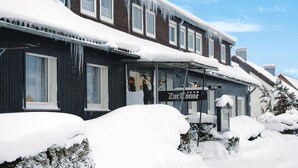 A building with a sign reading "Zur Schnei" covered in snow and icicles. - Geraumige Wohnung in Altenau mit Terrasse (Clausthal-Zellerfeld)