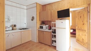 A compact kitchen with white cabinets, a microwave, a stove, and a refrigerator. - Holiday Apartment in Kopalino (Choczewo)