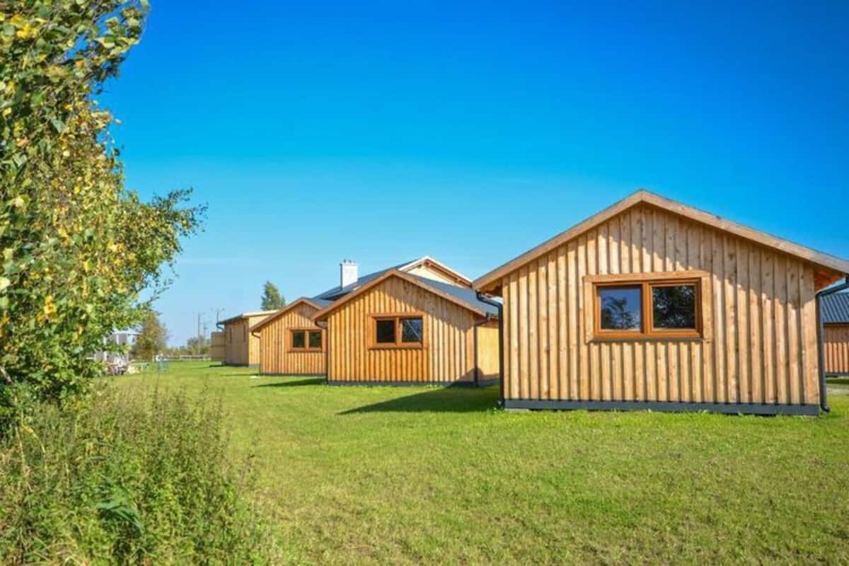 Une rangée de cabanes en bois aux toits en pente, disposées dans un champ verdoyant.