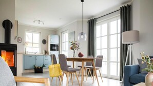 Ein modernes Wohnzimmer mit Kamin, Essbereich und großen Fenstern.