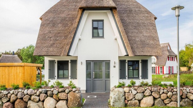 Ein Haus mit einem steilen Satteldach, einer mittleren Tür und einem kleinen Fenster darüber.