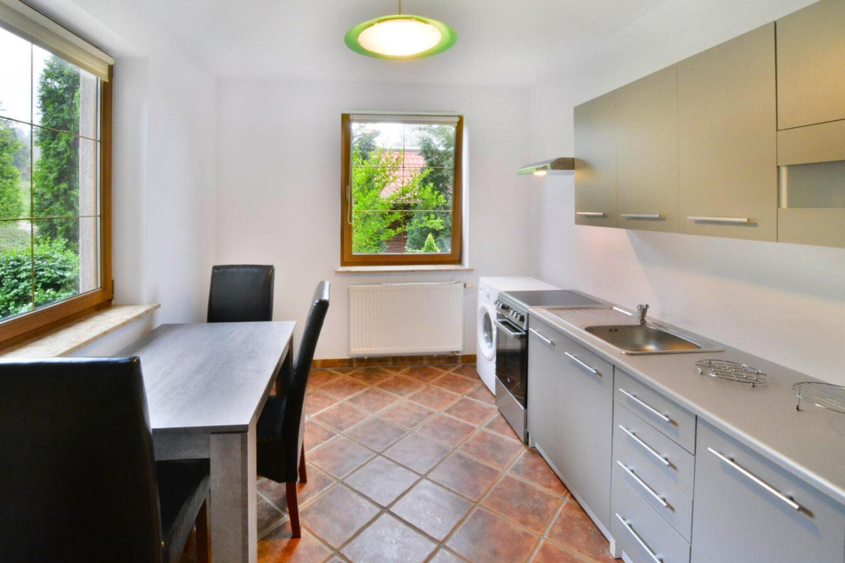 A compact kitchen with a dining table and chairs, a built-in oven, and a window with a view of greenery.