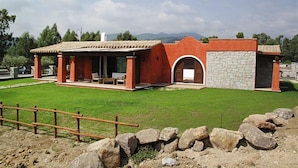 Un edificio moderno con fachada roja, detalles de piedra y un patio cubierto.