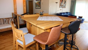 Une table à manger en bois, ornée d’un globe terrestre et de quelques papiers, entourée de chaises en bois et d’un canapé en cuir.