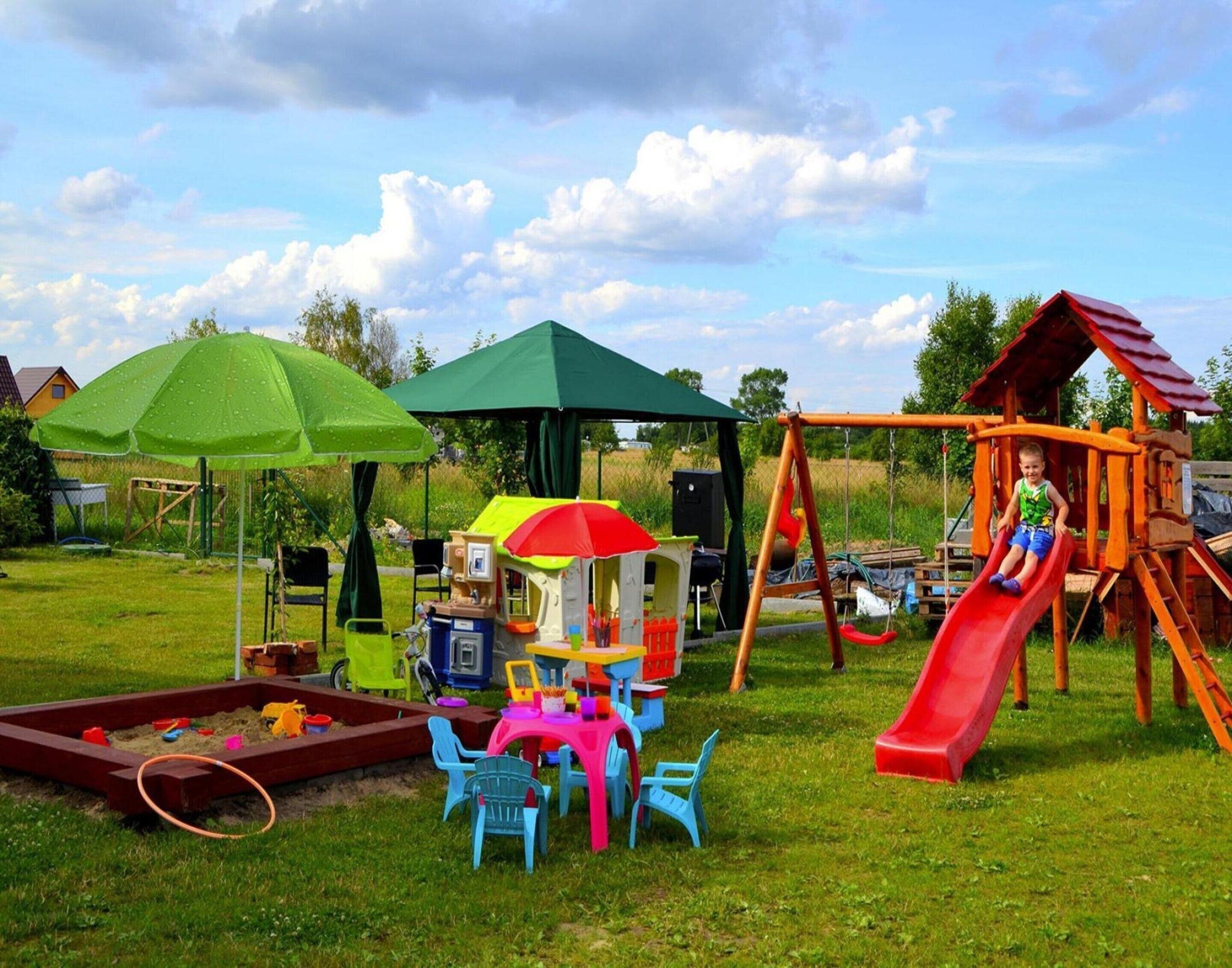 A playground with a slide, swings, and a playhouse.