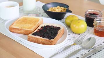 A breakfast tray with toast, jam, cereal, and fruit on a table.
