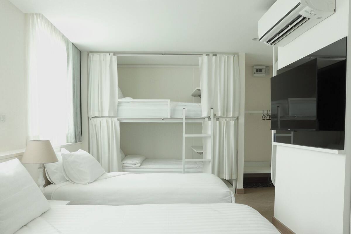 Ein Hotelzimmer mit Etagenbett, Schreibtisch mit Stuhl, Fernseher und Kleiderschrank.