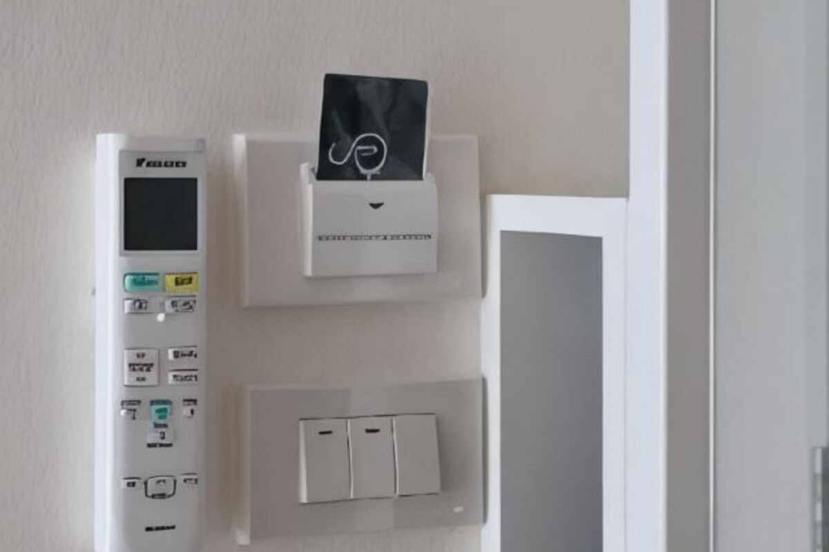Un panneau de commande doté d’un écran numérique, d’un distributeur de mouchoirs et d’une série d’interrupteurs fixés au mur.