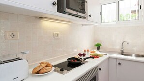 A modern kitchen with a built-in microwave, toaster, and induction cooktop. - Vacation Home, San Agustin (San Bartolomé de Tirajana)