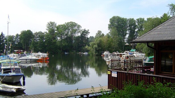 Un río tranquilo con barcas amarradas a un muelle de madera.