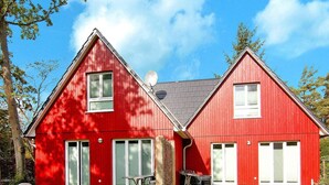 Ein rotes, zweistöckiges Haus mit einer Ziegelterrasse und einem kleinen Tisch im Freien.