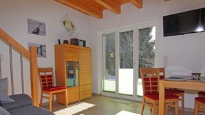 Ein Wohnzimmer mit einer Couch, einem Holzkasten und einem Esstisch mit Stühlen.