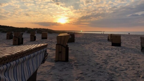 Ein Strand mit Liegestühlen und einer Holzterrasse.