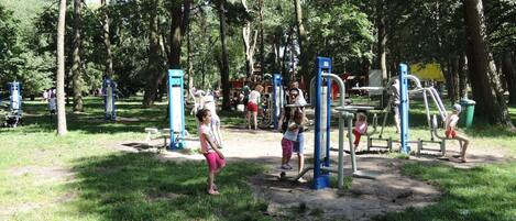 A park with exercise equipment and trees.