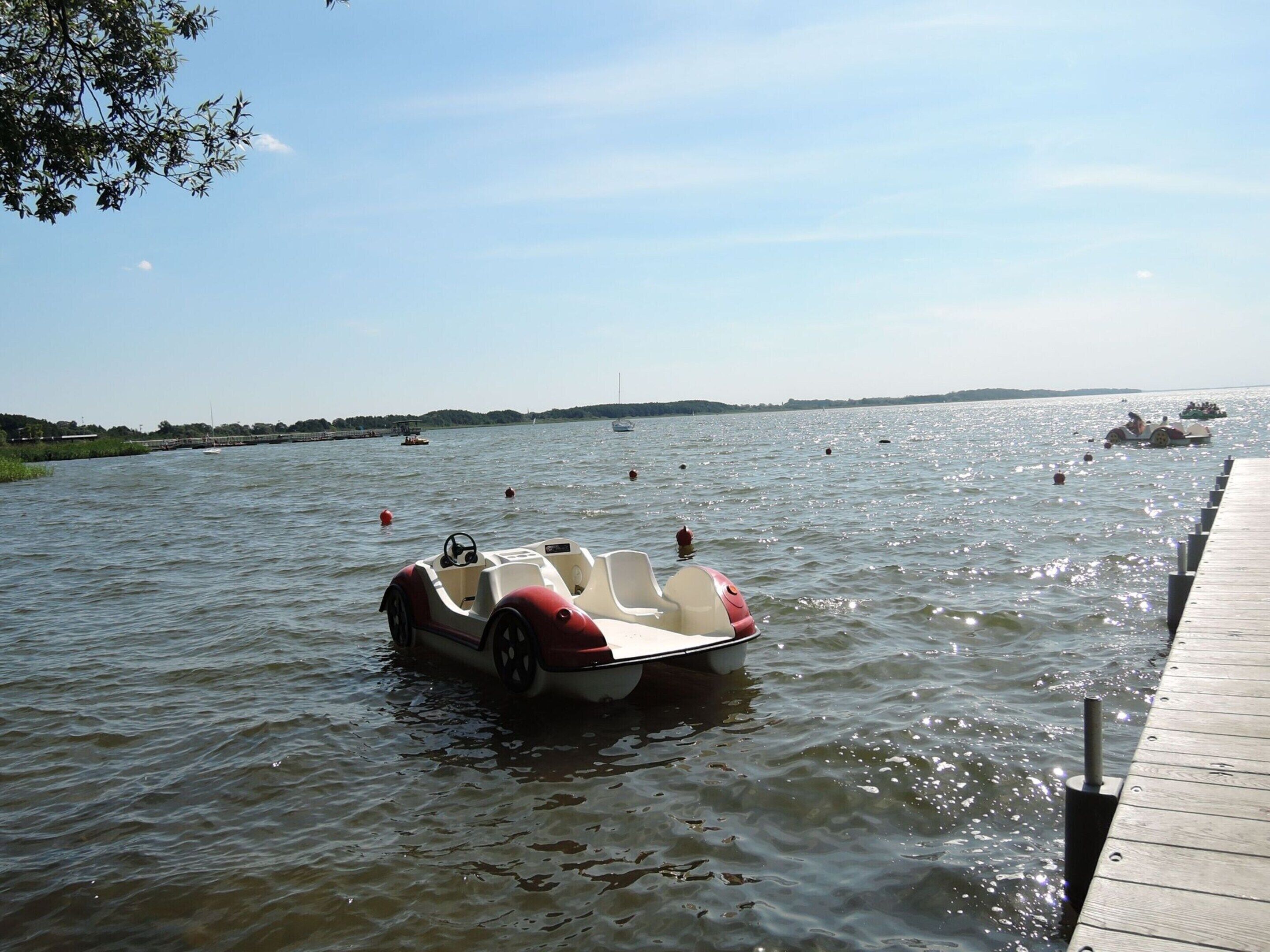 A boat docked at a pier with calm water and a clear sky.