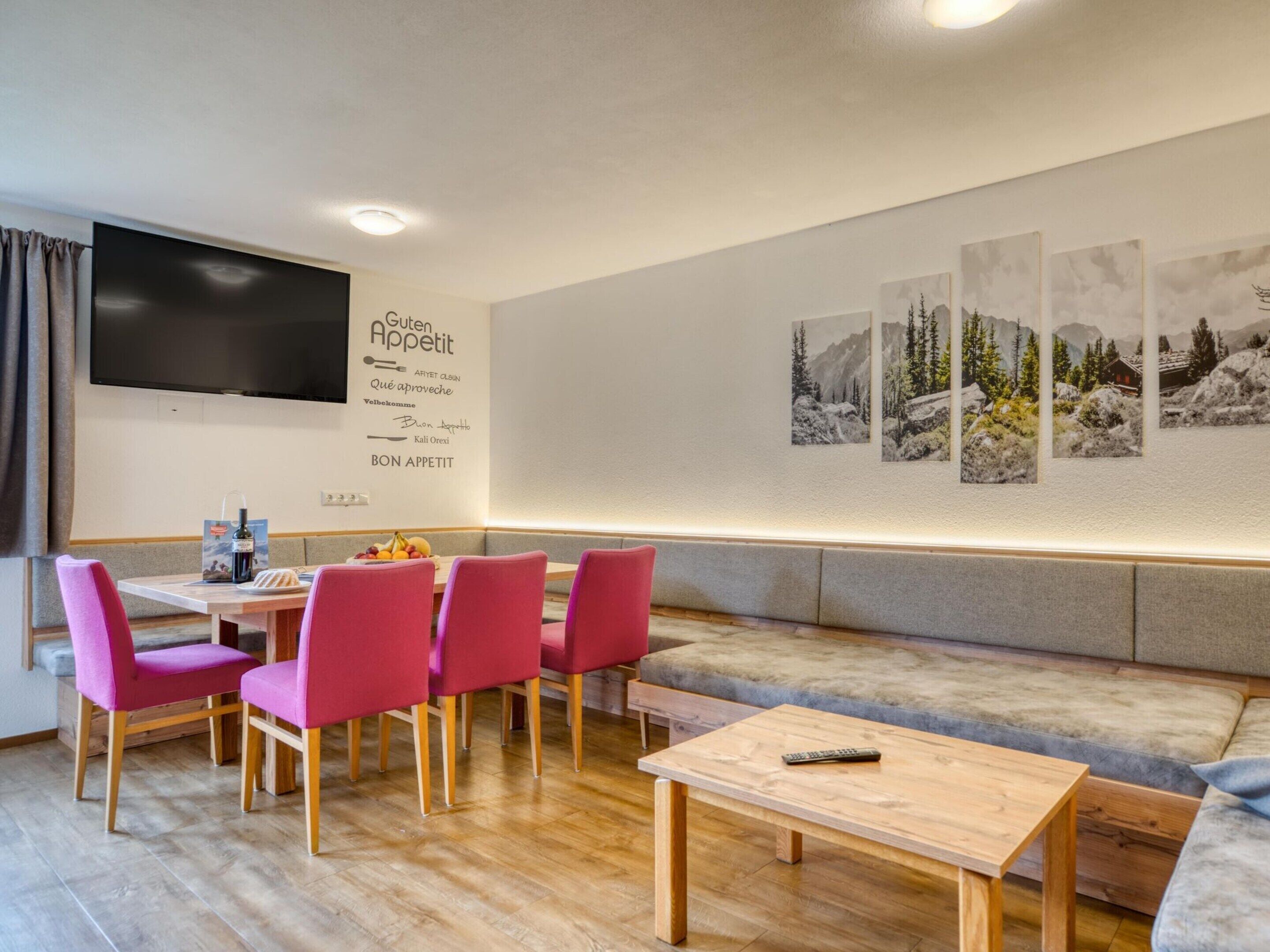 Una habitación de hotel moderna con comedor, un sofá y un televisor de pantalla plana.
