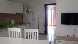 A modern kitchen with white cabinets, a dining table with two chairs, a refrigerator, and a TV mounted on the wall. - Holiday Home in Starigrad With Sea Views (Starigrad)