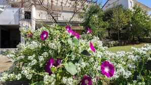 A building with a white facade and a red roof, surrounded by greenery and flowering plants. - Holiday Home in Starigrad With Sea Views (Starigrad)